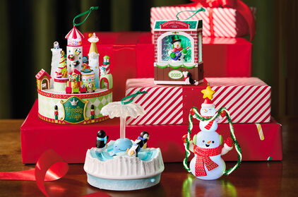 Four keepsake ornaments displayed in front of wrapped boxes